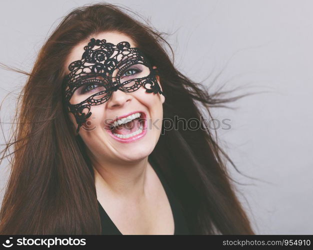 Happy pretty mysterious woman wearing black eye lace mask having tousled windblown long brown hair.. Mysterious woman wearing lace mask