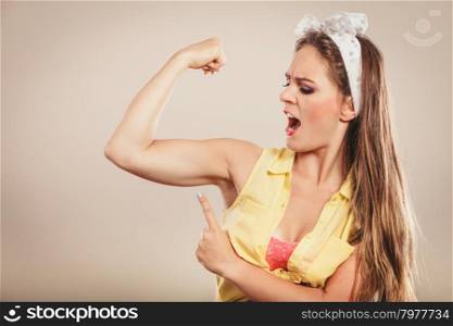 Happy pretty pin up girl showing off muscles.. Happy strong pretty pin up girl with hairband bow showing off muscles. Young gorgeous retro woman in studio.