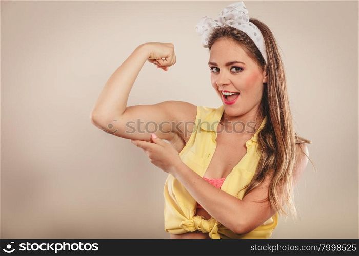 Happy pretty pin up girl showing off muscles.. Happy strong pretty pin up girl with hairband bow showing off muscles. Young gorgeous retro woman in studio.
