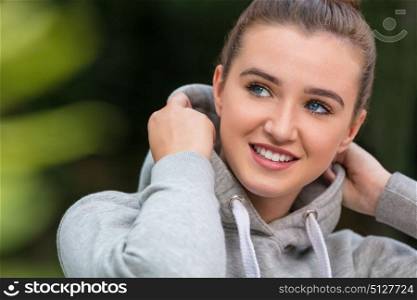 Happy pretty teenage female girl young woman with blue eyes and perfect teeth, smiling and wearing hoody outside in spring or summer