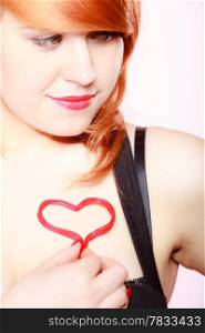 Happy redhair young woman smiling girl holding valentine red heart love symbol on pink. Valentines day. Studio shot.