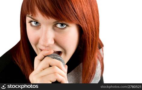 Happy redhead girl singing karaoke on a microphone. Studio shot.