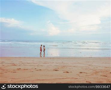 Happy romantic couple enjoying beautiful sunset walk on the beach. Pastel colors tone