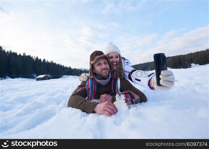 happy romantic couple have fun in fresh snow and taking selfie. Romantic winter scene in forest with young people