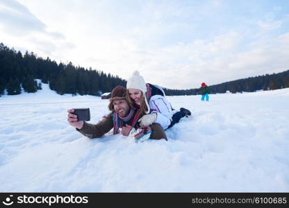 happy romantic couple have fun in fresh snow and taking selfie. Romantic winter scene in forest with young people