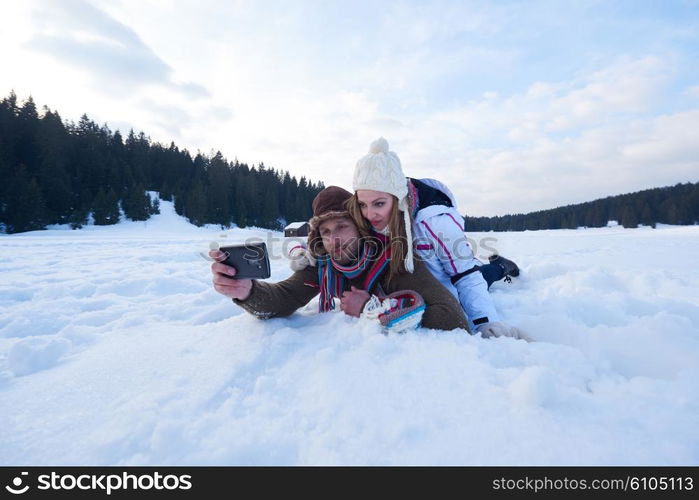 happy romantic couple have fun in fresh snow and taking selfie. Romantic winter scene in forest with young people