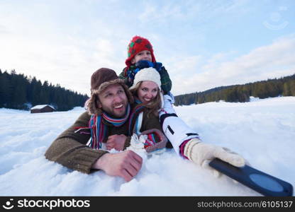 happy romantic couple have fun in fresh snow and taking selfie. Romantic winter scene in forest with young people