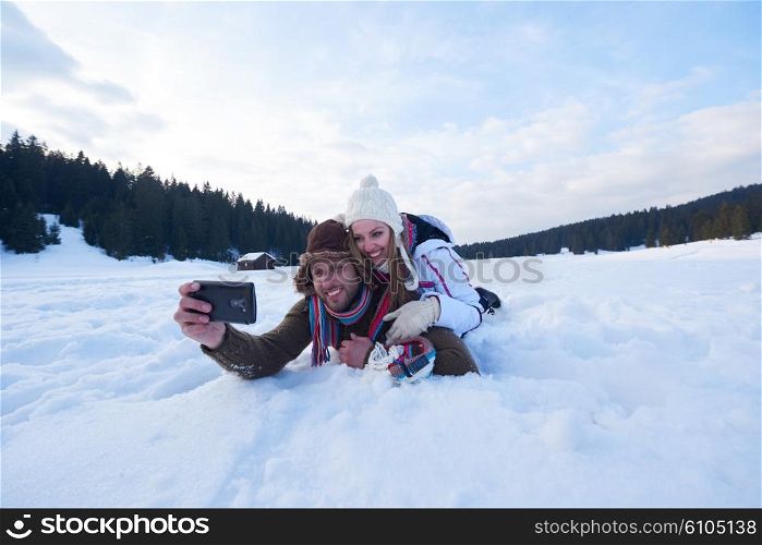 happy romantic couple have fun in fresh snow and taking selfie. Romantic winter scene in forest with young people