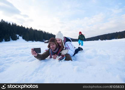 happy romantic couple have fun in fresh snow and taking selfie. Romantic winter scene in forest with young people