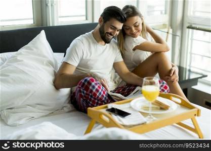 Happy romantic young couple having breakfast in bed
