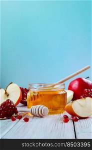 Happy Rosh Hashanah. Jar with honey, apples and pomegranates on a blue background. Jewish traditional religious holiday. Place for your text. Vertical photo.. Happy Rosh Hashanah. Jar with honey, apples and pomegranates on blue background. Jewish traditional religious holiday.