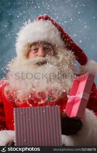 Happy Santa Claus opening his Christmas gift at North Pole