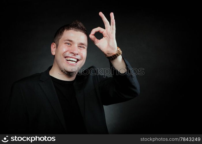 Happy Satisfied man gesturing the all right symbol, showihg ok sign black background