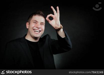 Happy Satisfied man gesturing the all right symbol, showihg ok sign black background