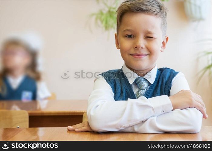 Happy schoolboy sitting at desk, first day in the school