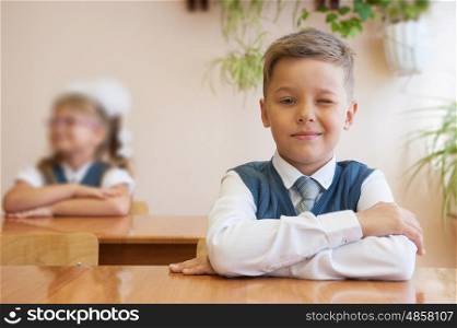 Happy schoolboy sitting at desk, first day in the school