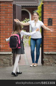 Happy schoolgirl running to her mother waiting for her after school