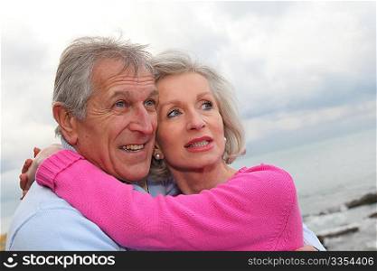 Happy senior couple embracing each other by the sea