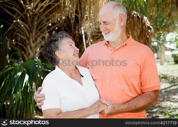 Happy senior couple holding hands and looking into each others eyes.