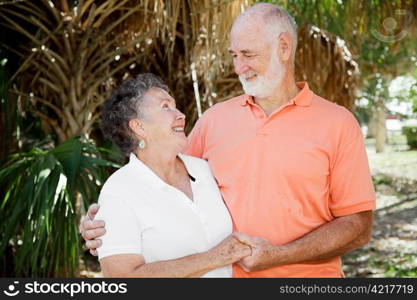 Happy senior couple holding hands and looking into each others eyes.