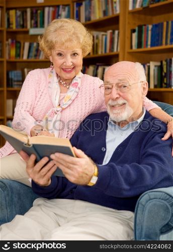 Happy senior couple reading together at the library.