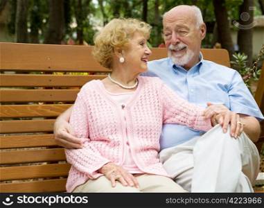 Happy senior couple relaxes together on a park bench.