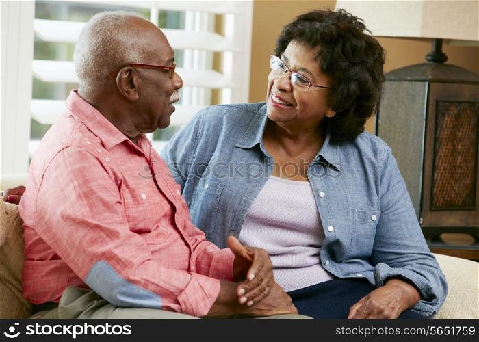 Happy Senior Couple Sitting On Sofa At Home