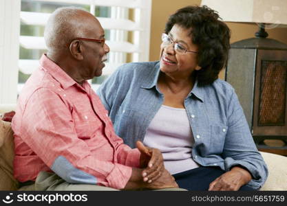 Happy Senior Couple Sitting On Sofa At Home
