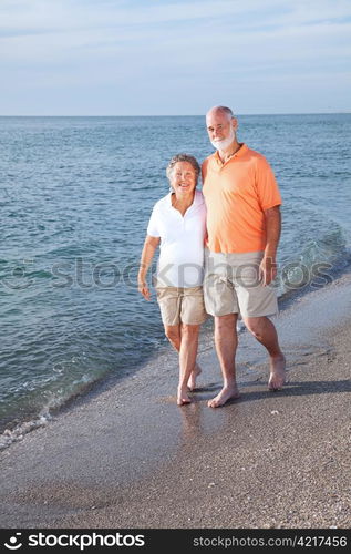 Happy senior couple take a stroll on a beautiful tropical beach.