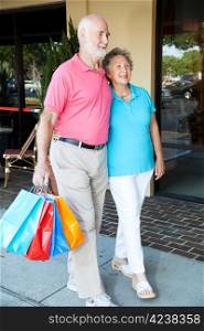 Happy senior couple walking at the mall with shopping bags.