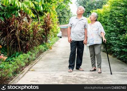 Happy senior couple walking together in the garden. Old elderly using a walking stick to help walk balance. Concept of  Love and care of the family And health insurance for family