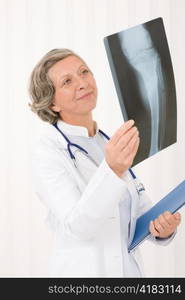 Happy senior doctor female looking at x-ray with stethoscope portrait