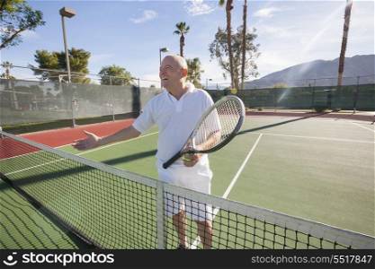 Happy senior male tennis player offering handshake on court