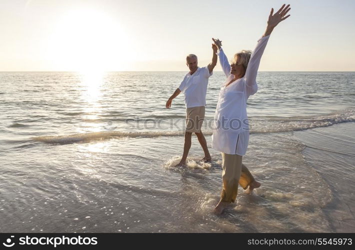 Happy senior man and woman couple dancing and holding hands on a deserted tropical beach at sunrise or sunset