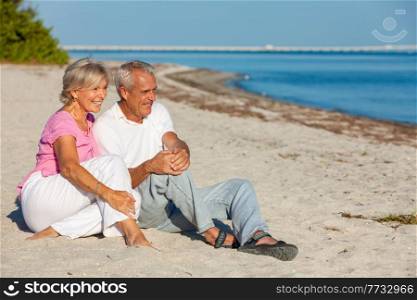Happy senior man and woman couple sitting, smiling and laughing on a sunny beach