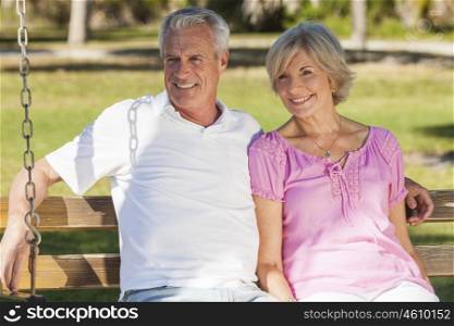 Happy senior man and woman couple sitting together on a park bench outside in sunshine