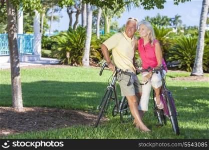 Happy senior man and woman couple together cycling on bicycles in a sunny green tropical park