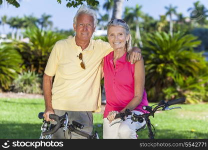 Happy senior man and woman couple together cycling on bicycles in a sunny green park