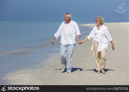 Happy senior man and woman couple walking and holding hands on a deserted tropical beach with bright clear blue sky
