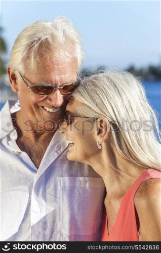 Happy senior man and woman romantic couple laughing together next to tropical sea or river with bright clear blue sky