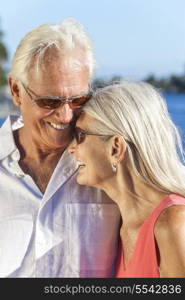 Happy senior man and woman romantic couple laughing together next to tropical sea or river with bright clear blue sky