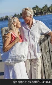 Happy senior man and woman romantic couple together embracing walking by tropical sea or river with bright clear blue sky