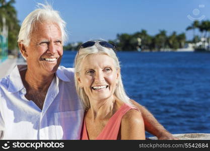 Happy senior man and woman romantic couple together looking out to tropical sea or river with bright clear blue sky