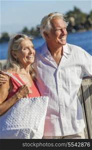 Happy senior man and woman romantic couple together looking out to tropical sea or river with bright clear blue sky