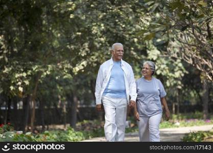 Happy senior man and woman walking at park