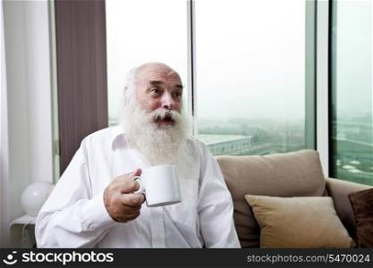 Happy senior man holding coffee cup at home