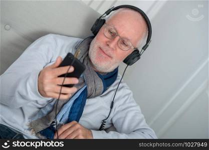 happy senior man in headphones listening to music at home