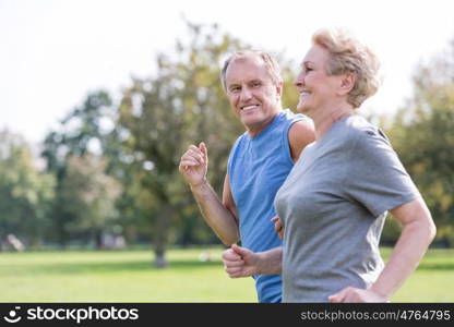 Happy senior man looking at woman while jogging in park