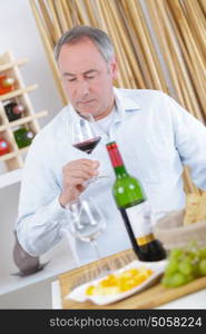 happy senior man tasting wine at home