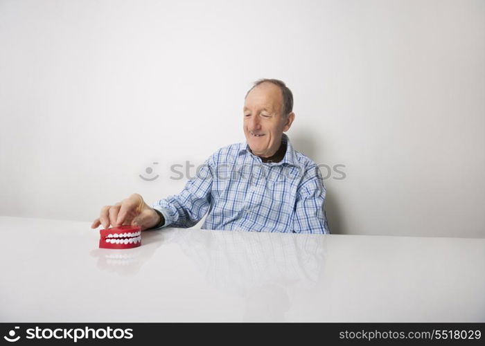 Happy senior man with dentures at table